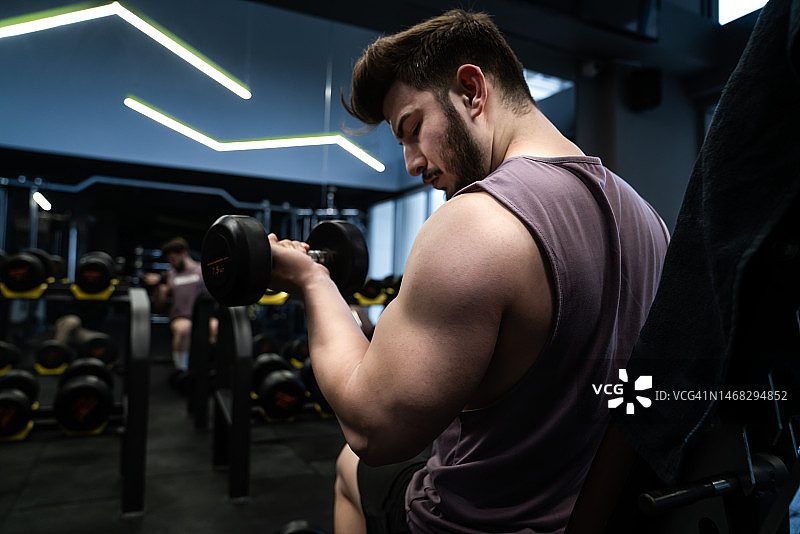 在健身房举重的强壮年轻男子侧面照图片素材