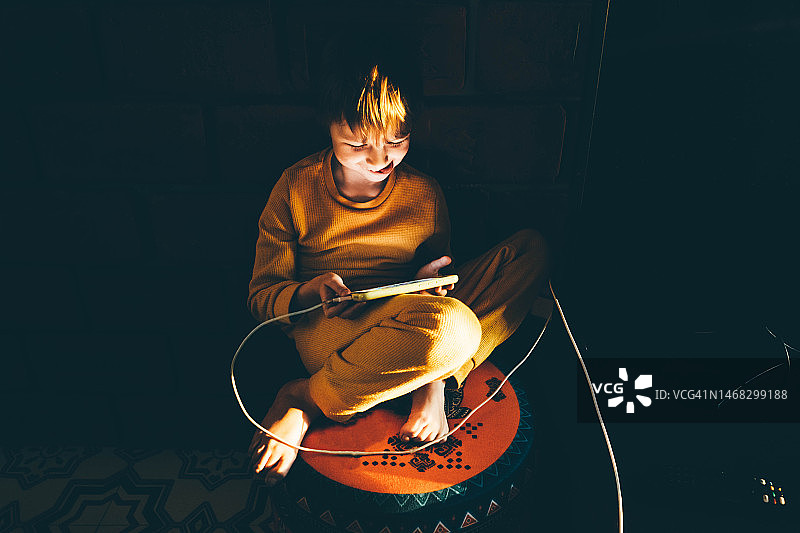 男孩在黑暗的卧室里使用智能手机图片素材