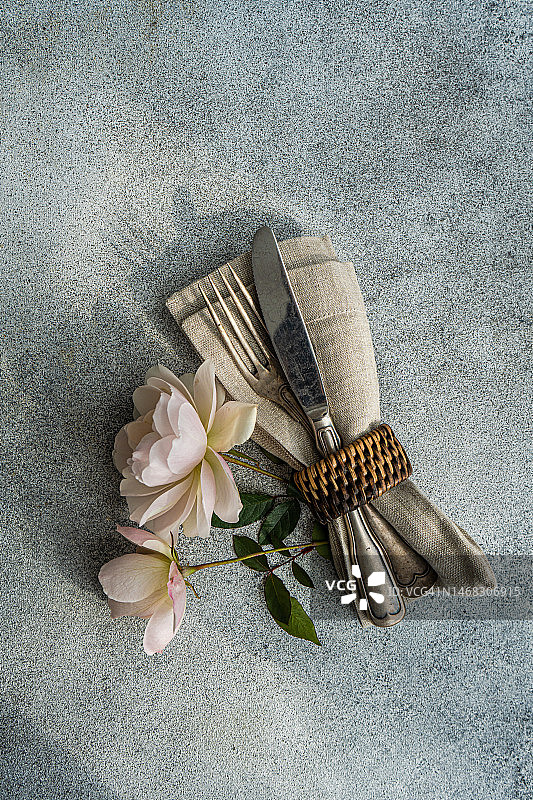 餐具套装在餐巾环中，桌上有白色玫瑰的顶视图特写图片素材