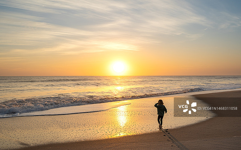 幼儿女孩在佛罗里达梅里特岛国家野生动物保护区琳达海滩欣赏美丽的日出图片素材