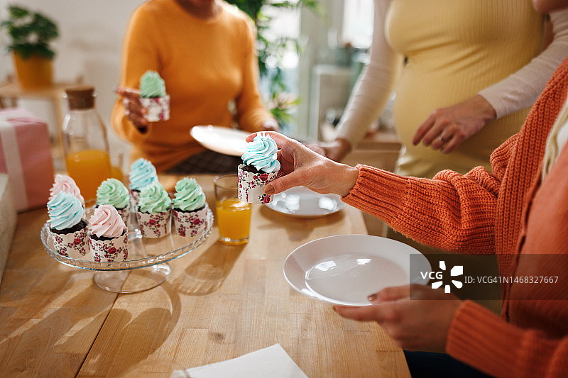 女友们在迎婴派对上拿着纸杯蛋糕图片素材