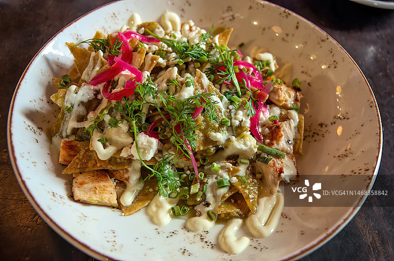 奇拉基莱斯配绿色萨尔萨酱：玉米片、鸡丝、奶油、科蒂哈奶酪和腌红洋葱图片素材