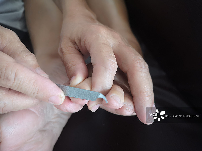 用指甲锉刀修剪脚趾甲图片素材