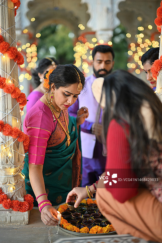印度传统节日期间，身穿传统服装的印度男女在宫殿大理石亭台的盘子里摆放油灯图片素材
