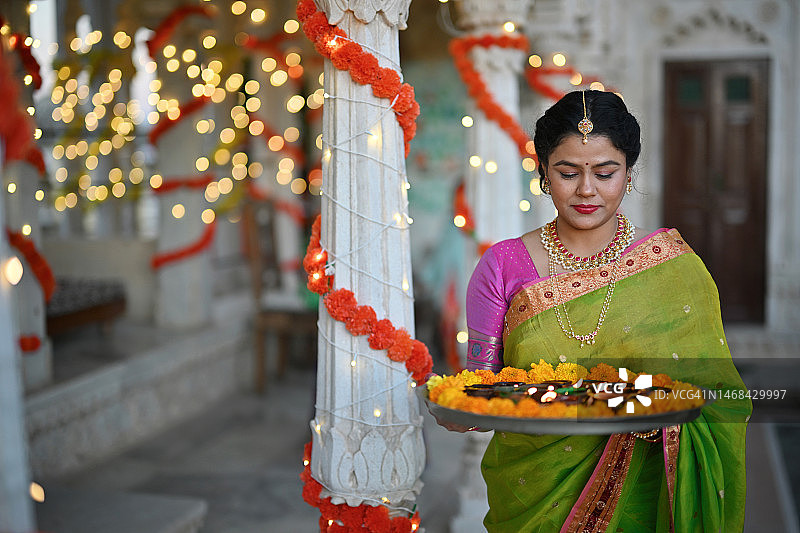 印度女性手持油灯（Diya），站在装饰有万寿菊的大理石宫殿亭子里图片素材