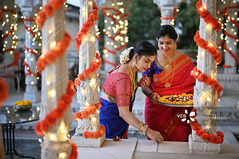 美丽的印度妇女穿着纱丽，用油灯（Diya）装饰大理石凉亭，为传统节日做准备图片素材