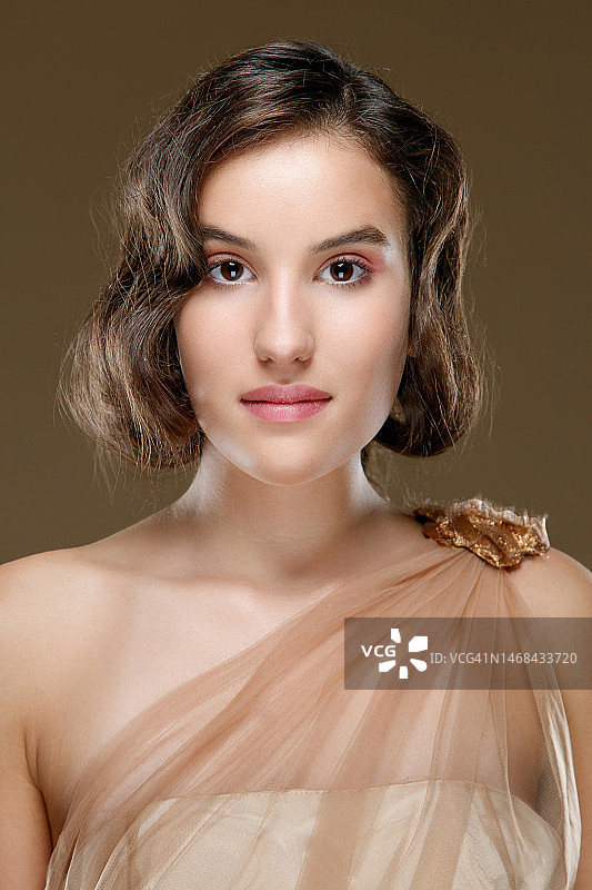 年轻深色头发女孩的肖像，身穿无肩带上衣，肩上披着香槟色面纱图片素材