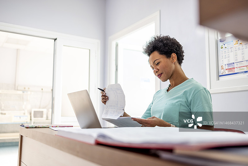 身穿绿色医疗制服的护士整理文件图片素材