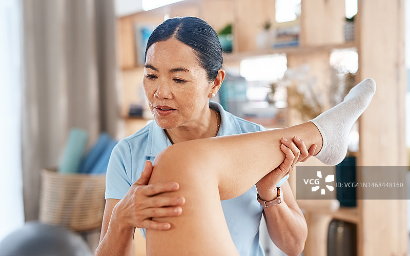 亚洲女性为患者进行腿部理疗或按摩，以改善身体健康。患者咨询理疗师以缓解膝盖疼痛，获得健康咨询图片素材