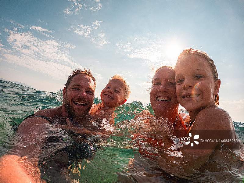 在海滩游泳的可爱白人男孩和他们的父母图片素材