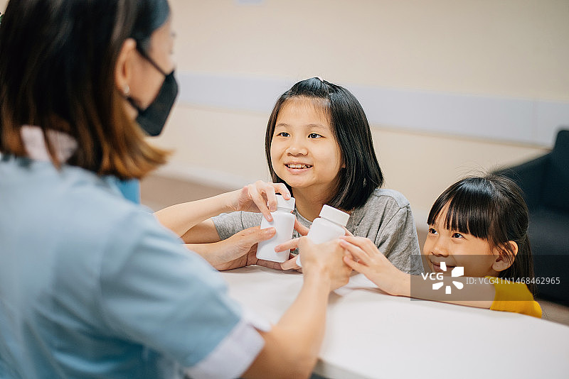 亚洲华人儿童帮父母在药房取药图片素材