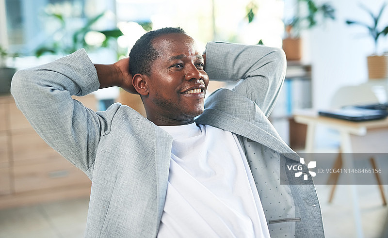 黑人男子在办公室伸展身体放松，轻松完成项目，实现目标，面带微笑展望商业前景图片素材