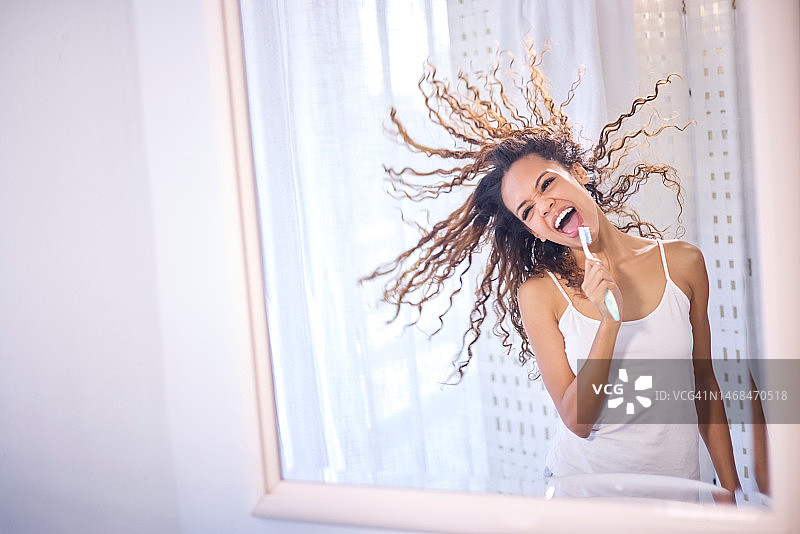 早上对着镜子唱歌、刷牙的快乐黑人女性图片素材