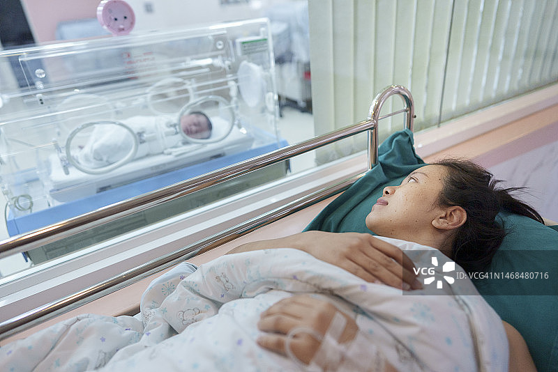 初见之爱：亚洲母亲喜出望外地看到在保育箱中的新生儿子图片素材