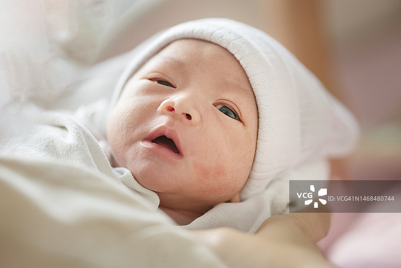 新生婴儿面部表情特写，躺在床上，有复制空间图片素材