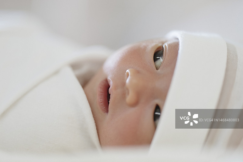 新生婴儿面部表情特写，躺在床上，有复制空间图片素材