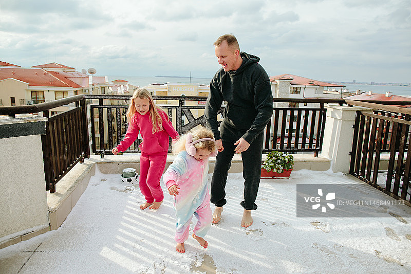露台上，父女赤脚在雪地里玩耍图片素材