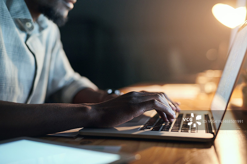 黑人男子深夜在办公室用笔记本电脑处理项目图片素材