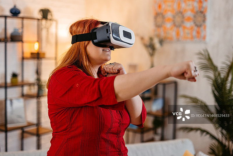 年轻女人在家戴着VR头显玩拳击游戏图片素材
