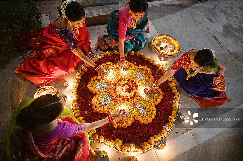身穿纱丽（印度传统服装）的印度妇女用油灯（Diya）装饰蓝果丽的俯视图图片素材