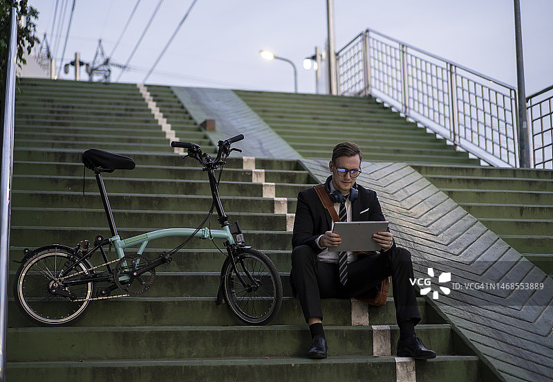 坐在楼梯上使用笔记本电脑的英俊男人图片素材