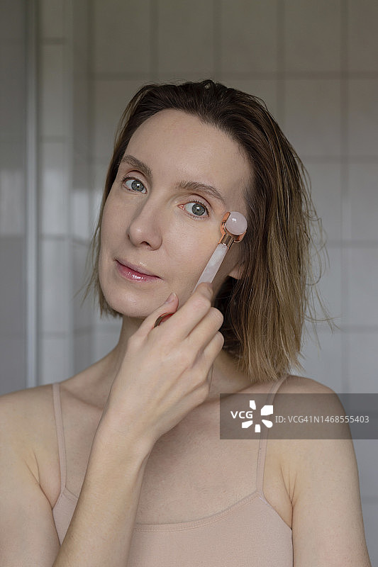 女人用玫瑰石按摩器按摩脸部，自我护理，基辅，乌克兰图片素材