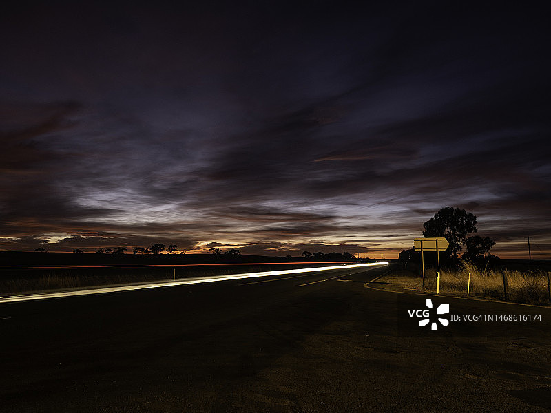 乡村公路上的日出与行驶的汽车图片素材