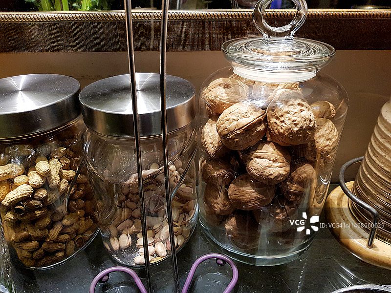 装满各种营养健康坚果的玻璃罐：开心果、核桃和花生图片素材