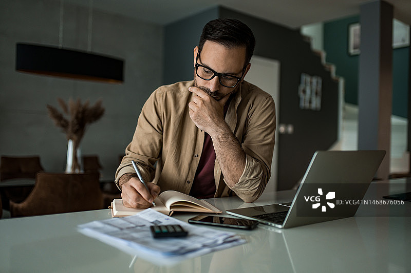 在家处理财务账单和税务的年轻男人图片素材