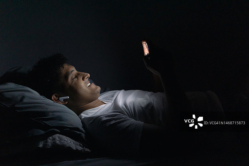 晚上使用手机的西班牙裔男人图片素材