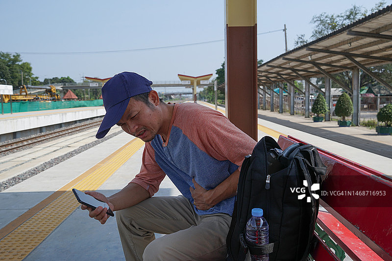 亚洲男人在火车站旅行时胃痛图片素材