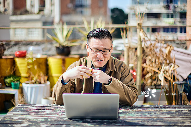 在露台上使用笔记本电脑进行视频会议的中国男商人图片素材