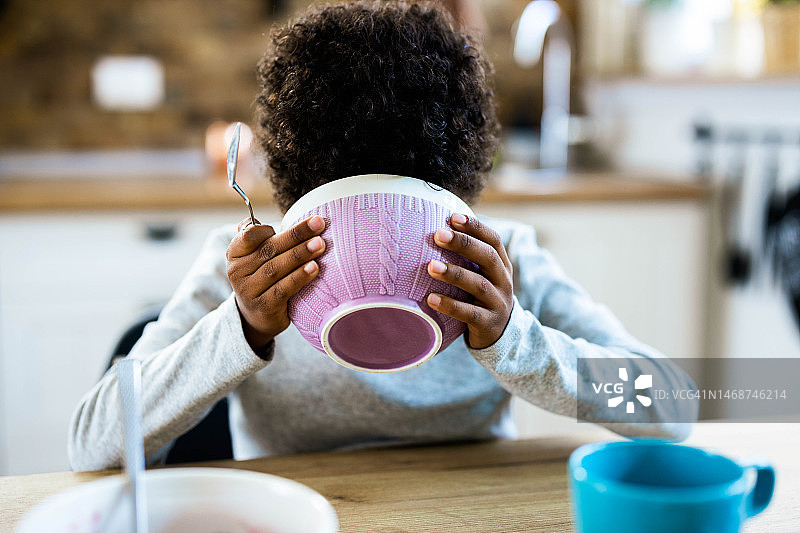 黑人小孩在餐桌旁用碗吃早餐图片素材