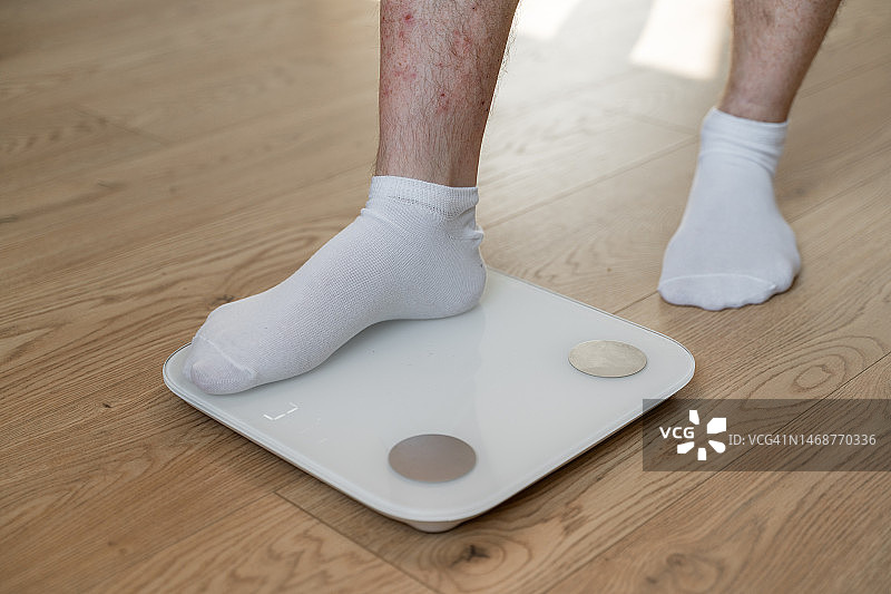 中年男人在家踩体重秤图片素材