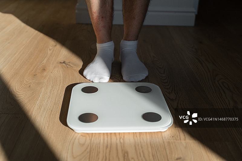 中年男人在家踩体重秤图片素材