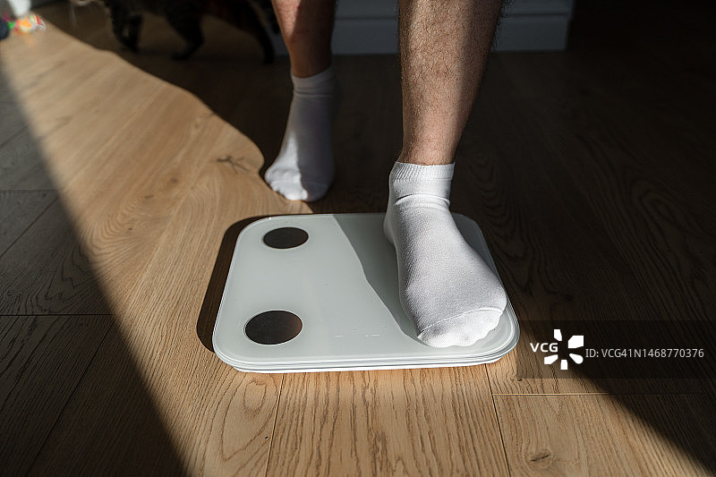 中年男人在家踩体重秤图片素材