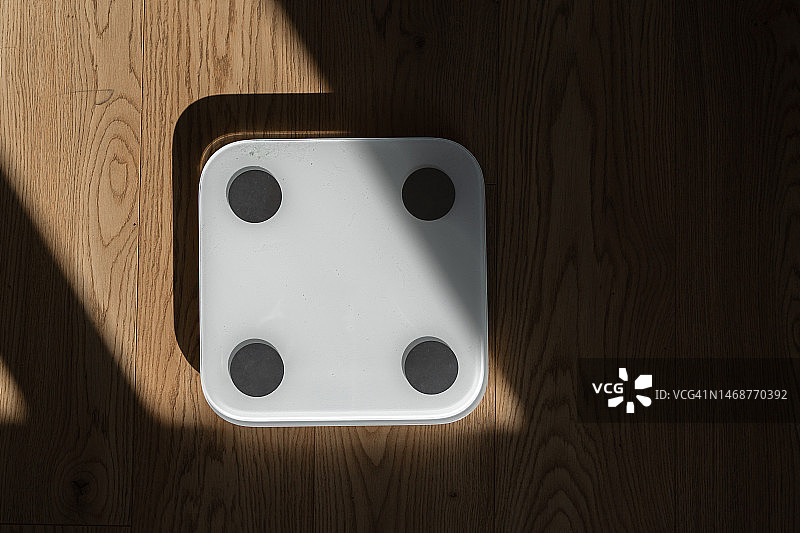 阳光和阴影下的木地板上的体重秤图片素材