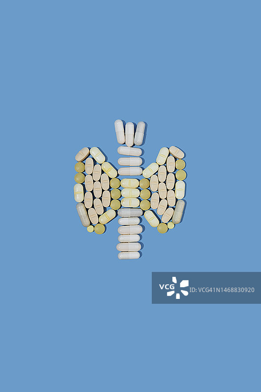 蓝色背景上人形甲状腺形状的药丸图片素材