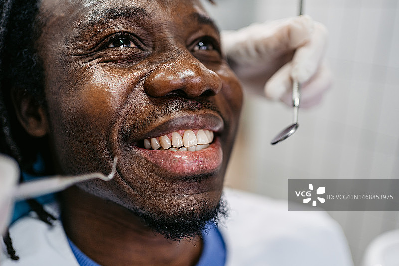 年轻男人在牙医诊所接受牙科治疗图片素材