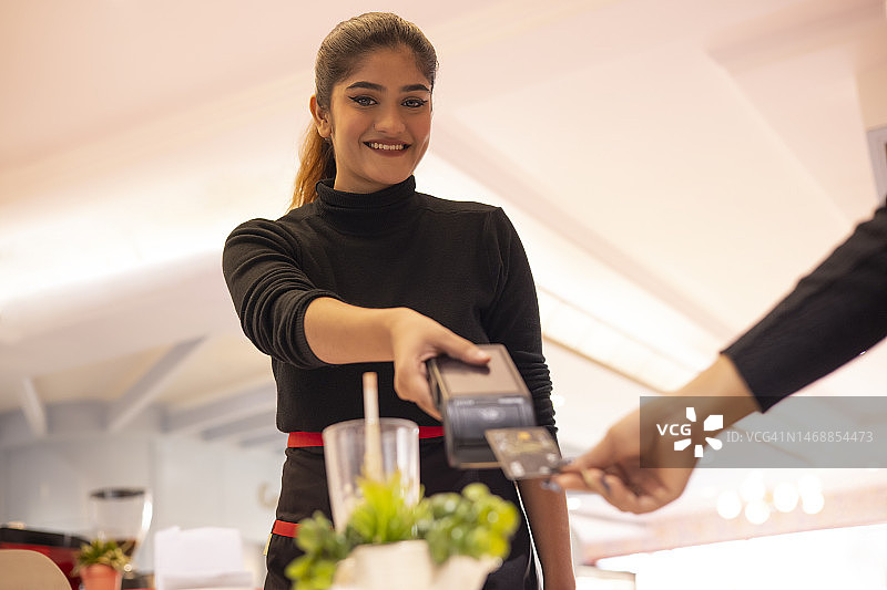 服务员手持读卡器，顾客用信用卡支付图片素材