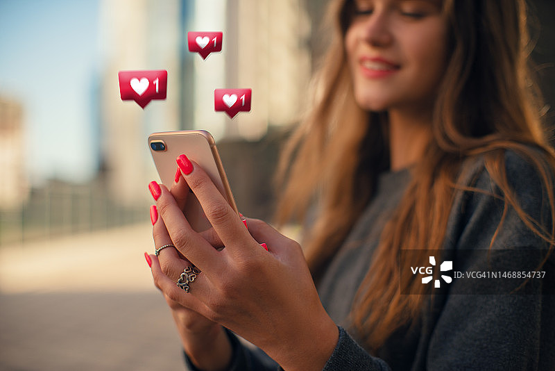年轻女人使用现代手机在社交媒体上点赞图片素材