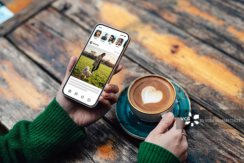 年轻女子在喝咖啡时使用社交媒体App的鸟瞰图图片素材