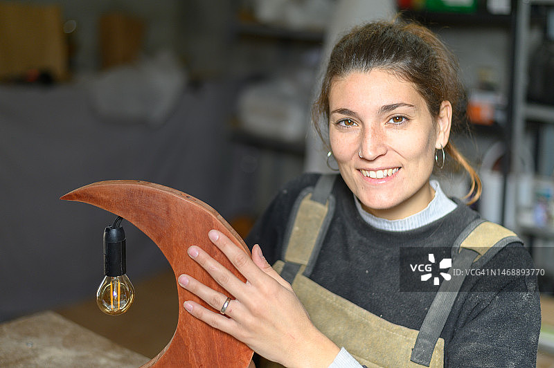 工匠展示月亮形状的木制灯图片素材