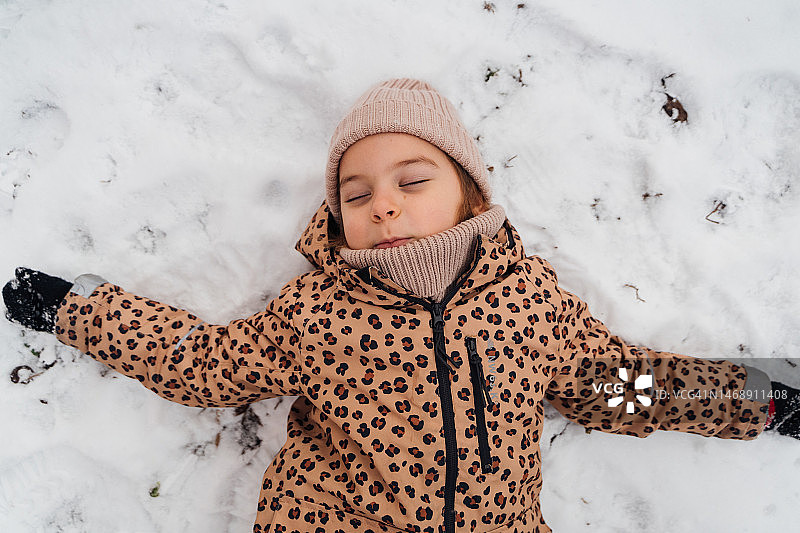 儿童躺在雪地上的俯视图图片素材