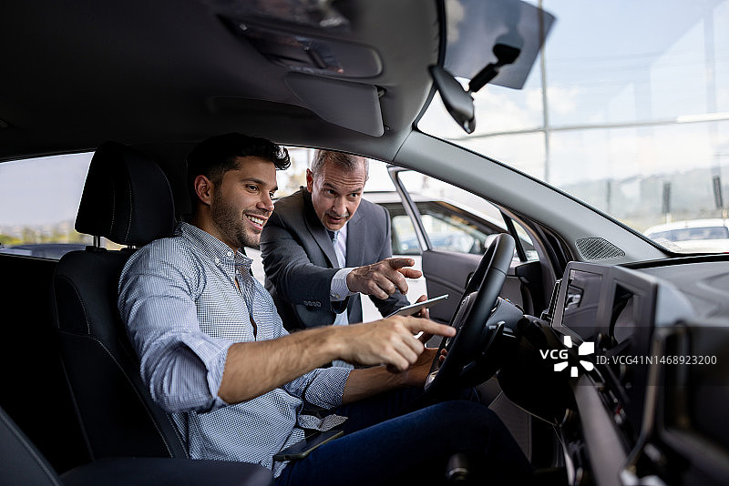 推销员在经销店向顾客展示汽车内部图片素材