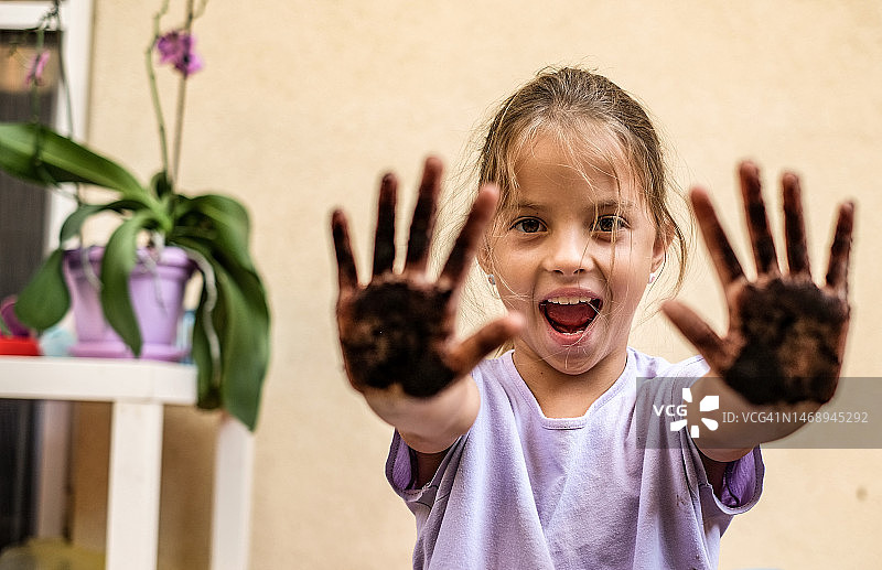 一个小女孩向镜头展示她脏兮兮的手的肖像图片素材