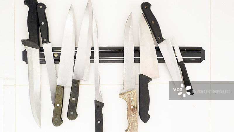厨房白色台面上磁性刀架上的金属刀具特写图片素材