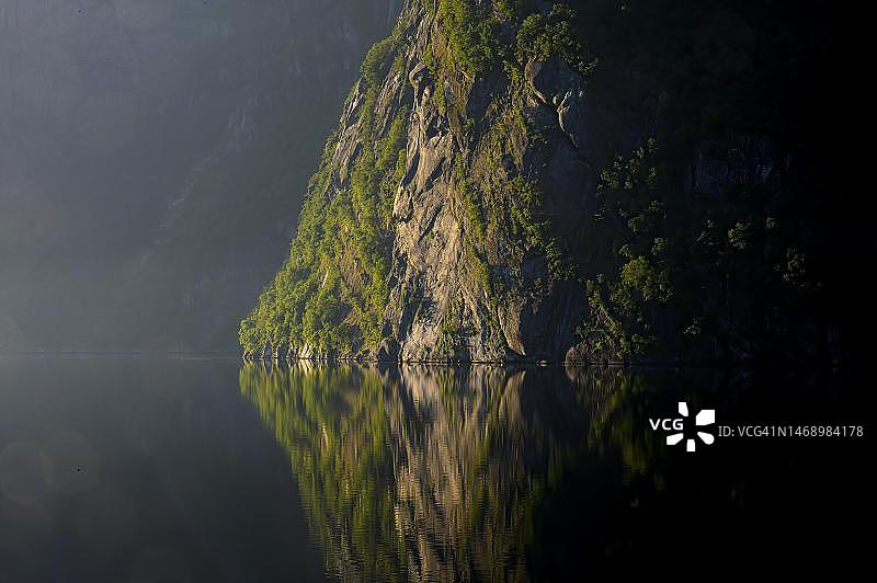 吕瑟峡湾陡峭的岩石岸边，挪威罗加兰郡松厄桑以东的早晨光线和渡轮图片素材