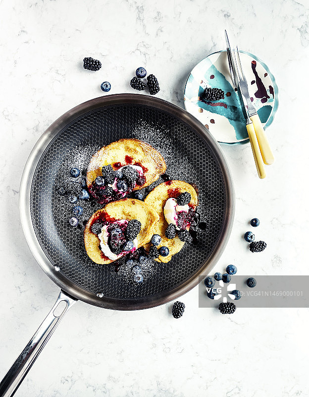 白色背景煎锅中的浆果法式吐司图片素材