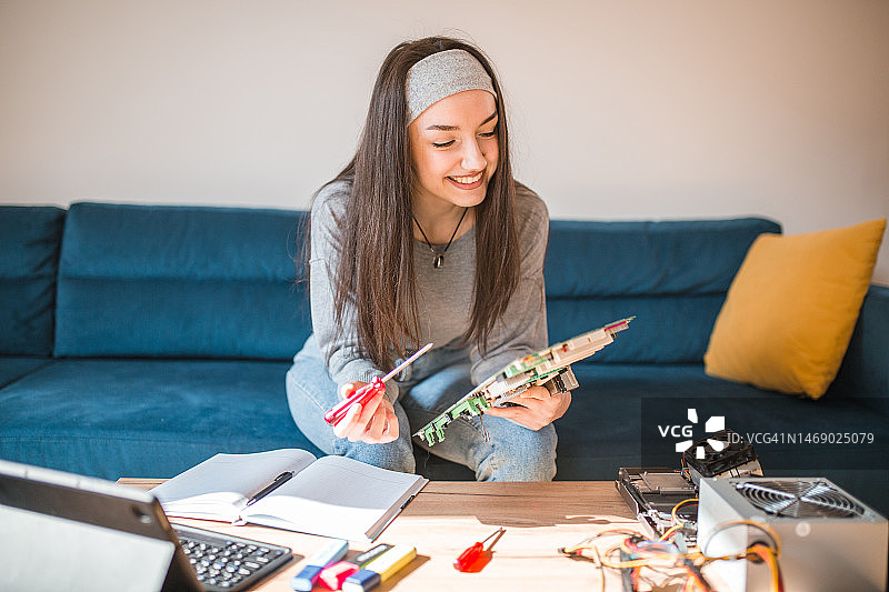 女学生在线学习电脑硬件，使用螺丝刀拆卸主板图片素材